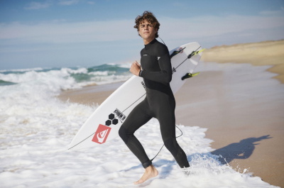 Surfer im Quiksilver Neoprenanzug mit Surfboard am Strand