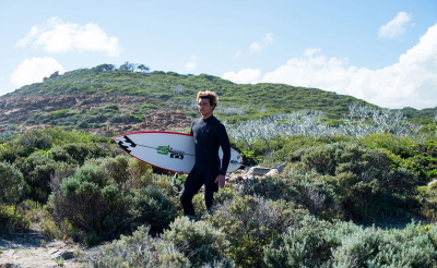 Surfista con una muta eco realizzata con materiali riciclati e senza neoprene