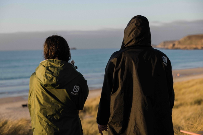 Nadadora de agua fría envuelta en un poncho cambiador impermeable forrado de polar en una playa de invierno