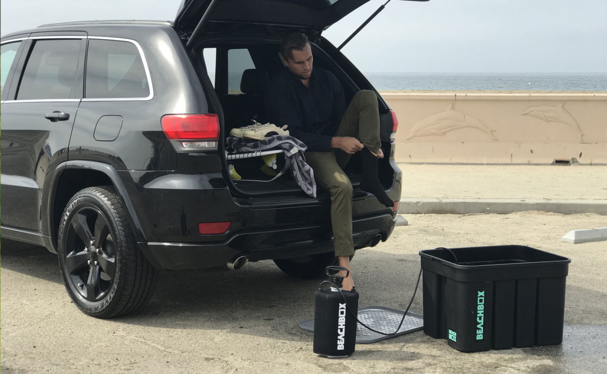 Man in his car next to a beach box shower