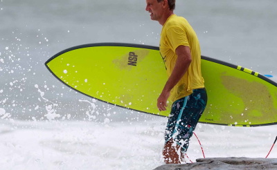 Uomo che corre verso il mare con una tavola da surf